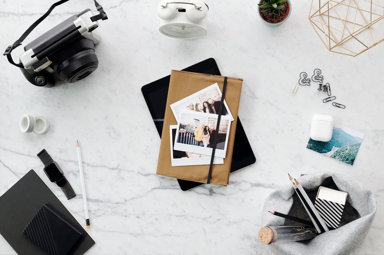 Elevated view of a stylish workspace with camera, photos, and office supplies on marble.